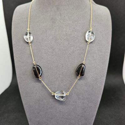 un collier composé de perles en verre noires et transparentes montées sur une chaîne en or