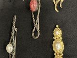 six pairs of brooches and hair clips on a black surface