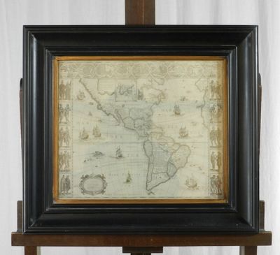 Une vieille carte du monde est exposée dans un cadre en bois.