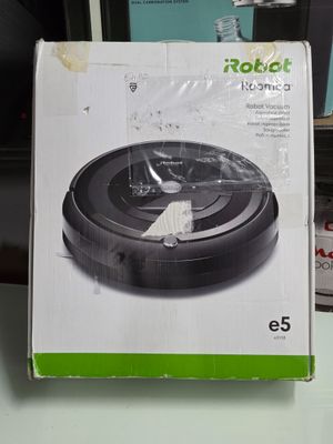 emballage d'un aspirateur robot posé sur une table à côté d'une bouteille d'eau
