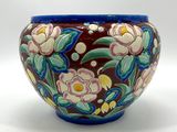 un vase avec des fleurs peintes dessus, posé sur une table