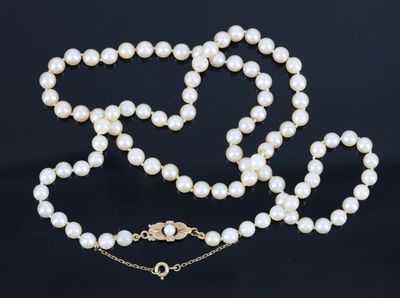 un collier de perles blanches avec un fermoir en or sur fond noir