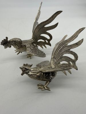 pair of silver plated rooster figurines on white background