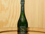 une bouteille de vin posée sur un tonneau en bois