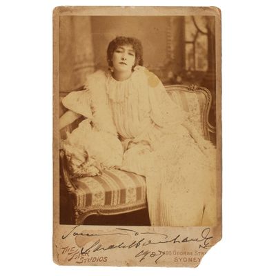 une vieille photo d'une femme assise sur un canapé avec un ours en peluche