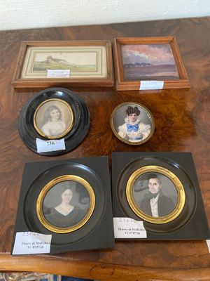 several framed portraits of people are on display on a table