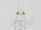 Gros plan sur une bague en or ornée d'une perle