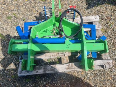 une photo d'une charrue de tracteur verte posée sur une palette en bois