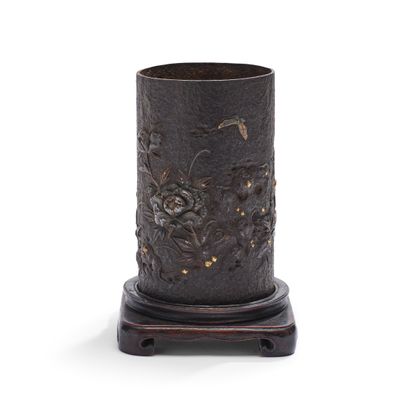 un vase noir orné de fleurs, posé sur un socle en bois