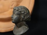 a small bronze bust of a woman next to a plate