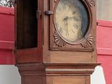 a wooden grandfather clock that is on the side of a building
