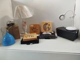 une table sur laquelle se trouvent une lampe, une horloge, une radio et d'autres objets