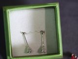 a pair of earrings in a green box on a table