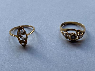 deux bagues en or ornées de perles, posées sur une table