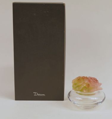 un vase en verre contenant une fleur, à côté d'une boîte noire