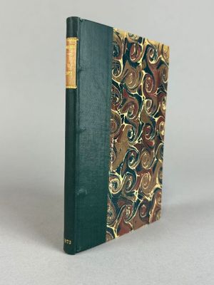un livre vert à la couverture dorée et noire posé sur une table