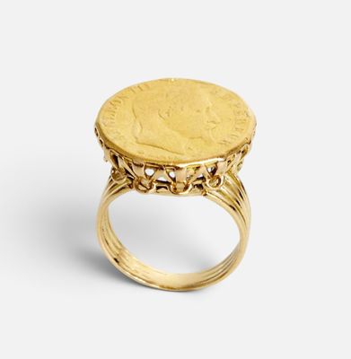 un gros plan d'une bague en forme de pièce d'or sur fond blanc