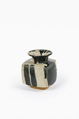 un vase noir et blanc posé sur une surface blanche
