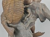 statue of a winged man on a rock with a bird on his back
