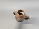 a small brown vase with a handle on a white surface