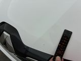 a person holding a ruler in front of a white car