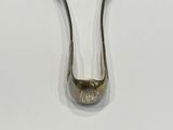 a silver spoon on a white surface with a spoon sticking out of it