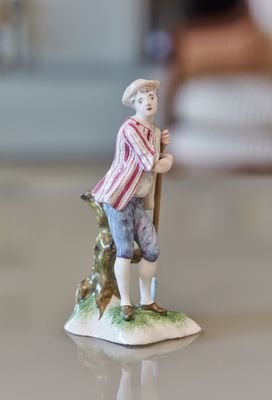 une figurine représentant un homme tenant un bâton, posée sur une table
