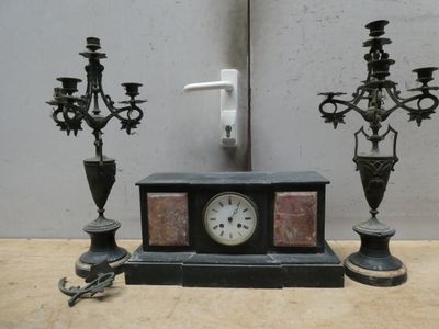 une horloge posée sur une table à côté de deux chandeliers