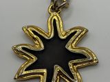 a close up of a gold and black star pendant on a chain