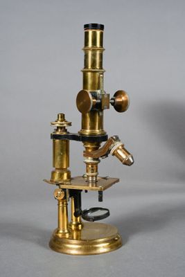an antique brass microscope with a wooden base and a metal stand
