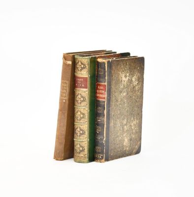 three old books are stacked on top of each other on a white surface
