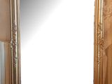 un grand miroir posé par terre à côté d'un vase