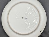 a white plate with a silver rim on a table