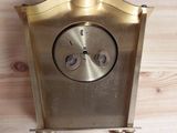 a gold clock that is on a wooden table