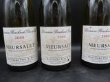 trois bouteilles de vin sont alignées sur une surface noire