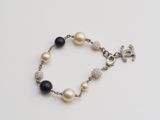 a close up of a bracelet with pearls and a cross on it