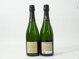 deux bouteilles de champagne posées l'une à côté de l'autre sur une surface blanche