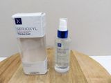 a bottle of serum next to a box on a table