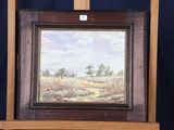 une peinture à l'huile représentant un paysage, posée sur un chevalet, avec un fond bleu
