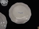 a white plate with blue writing on it next to a white vase