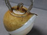 a brown and white tea pot with a silver handle