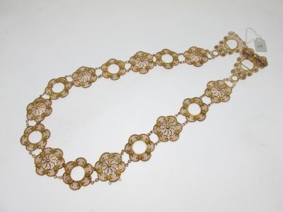 gros plan d'un bracelet en chaîne en or sur une surface blanche