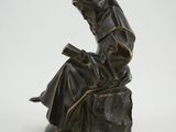 statue of a woman sitting on a rock reading a book