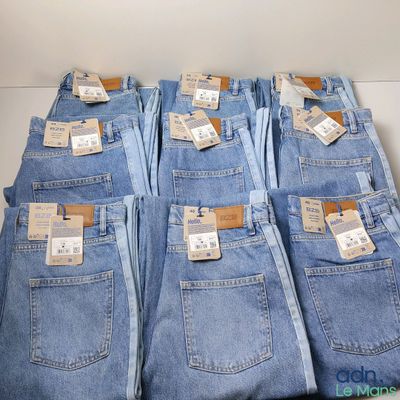 cinq paires de jeans bleus sont empilées les unes sur les autres