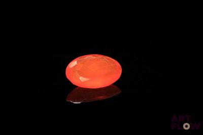une image représentant une pierre orange lumineuse posée sur une surface noire