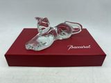 La figurine en verre représentant une paire de chaussures est posée sur une boîte rouge.