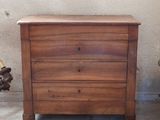 a small wooden chest of drawers next to a chair