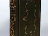 an old black book with gold trim sitting on top of a white surface