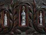 three statues on the side of a wooden door