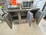 stainless steel counter top with two open doors and a microwave on top